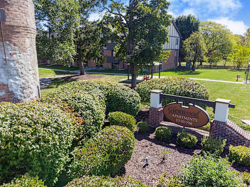 A sign for Glenwood Apartments is surrounded by green bushes.