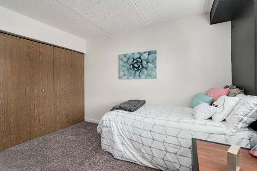 A bedroom with a bed, pillows, and a painting on the wall.