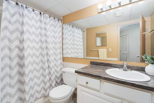 A bathroom with a white toilet, a sink, and a shower curtain.