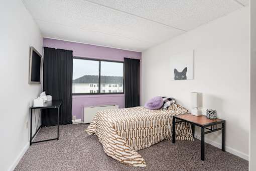 A bedroom with a bed, nightstand, and window with a view.