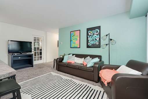 A living room with a brown couch and a striped rug.
