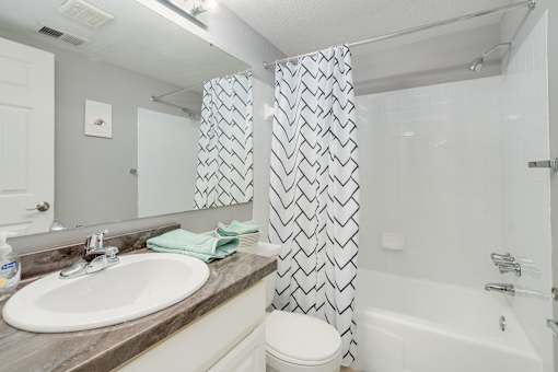 A bathroom with a white sink and a shower curtain with a black and white pattern.