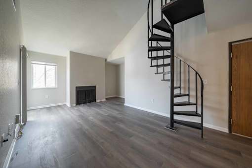 Open concept living room with spiral staircase at Alpine Slopes Apartments near Grand Rapids, MI