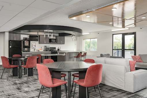 A modern kitchen with red chairs and a black table.