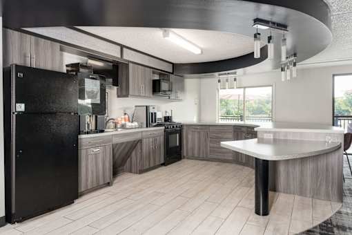 A modern kitchen with a black fridge and wooden cabinets.