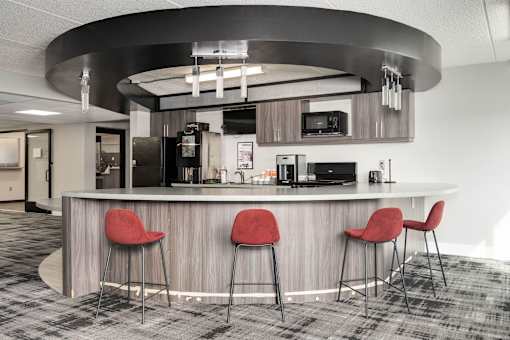 A modern bar area with a curved counter and three red stools.