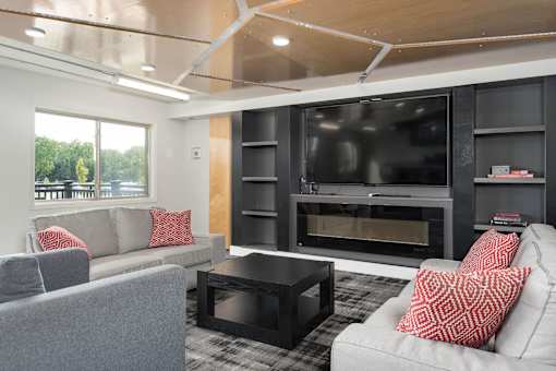 A modern living room with a grey couch, a black coffee table, and a black television.