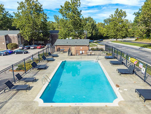 A large outdoor swimming pool surrounded by a fence and lounge chairs.