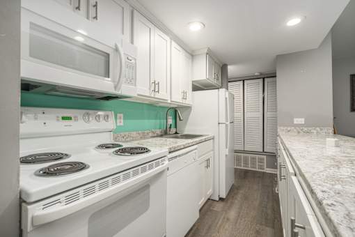 A white kitchen with a stove top oven and a microwave above it.