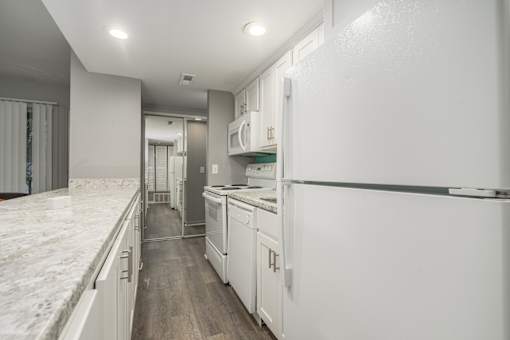 A white kitchen with a marble counter top.