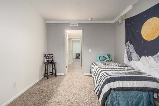 A bedroom with a bed, a chair, and a poster of the moon on the wall.