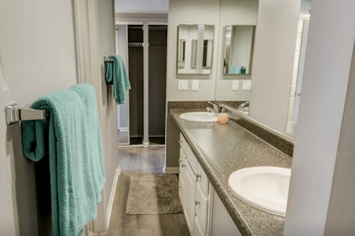 A bathroom with a sink, mirror, and towel rack.