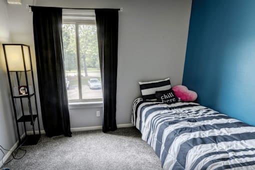 A bedroom with a striped bedspread and a window with curtains.