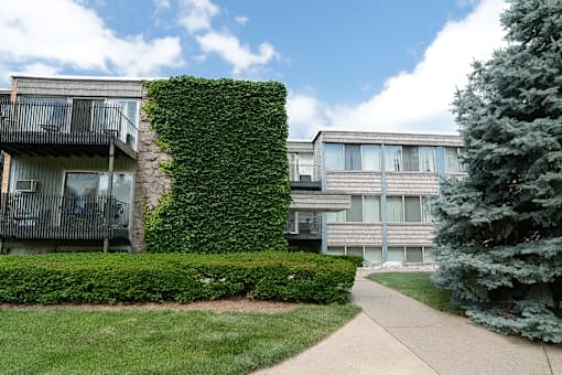 A building with a green hedge on the side.