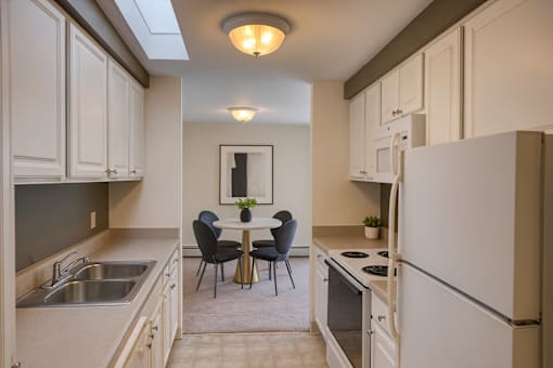 A kitchen with white cabinets and a table set for two.