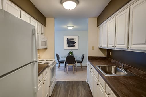 A kitchen with white cabinets and a white refrigerator.