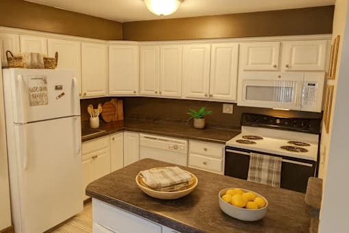 A kitchen with white cabinets and a white refrigerator.