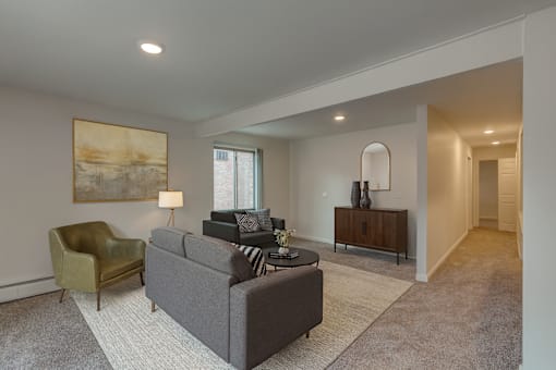 A living room with a grey couch, a green chair, and a painting on the wall.