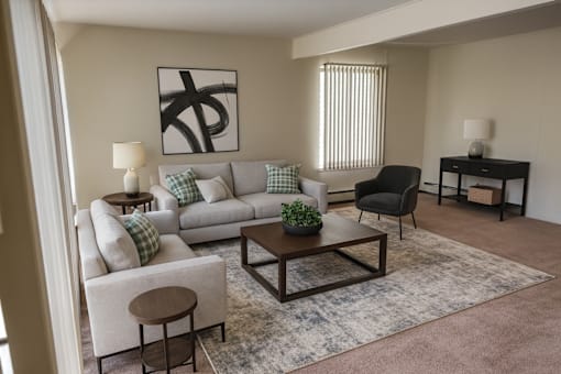 A living room with a grey couch, a black chair, a wooden coffee table, and a painting on the wall.