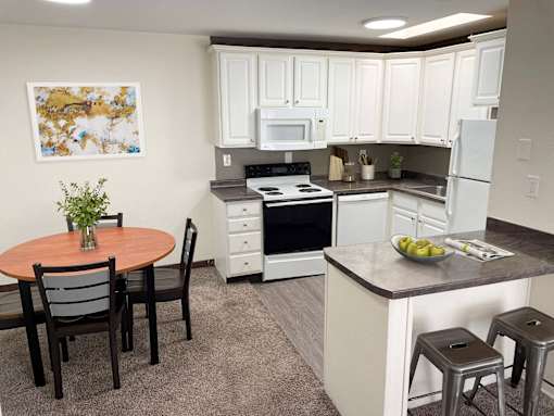 a kitchen with white cabinets and a table and chairs