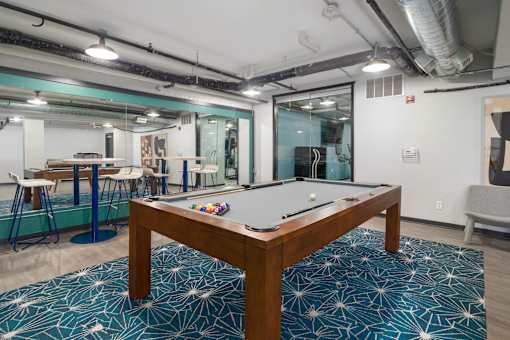 a pool table sits in the middle of a room with a bar in the background