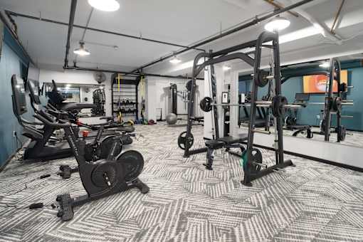 a spacious fitness room with cardio machines and weights