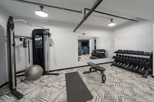 a spacious fitness room with cardio machines and weights