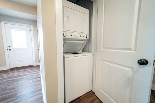 A white door is open to a small kitchen with a dishwasher and oven.