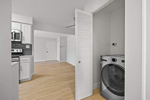 A modern kitchen with a washing machine in the corner.
