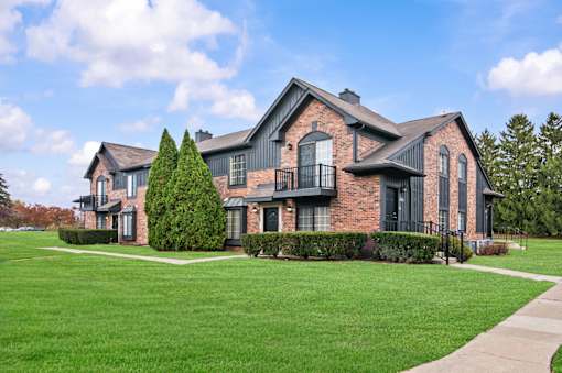 A large house with a black iron fence and a green lawn.