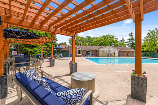 A wooden pergola over a pool area with a blue lounger.