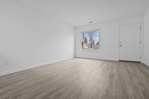 an empty living room with white walls and a window