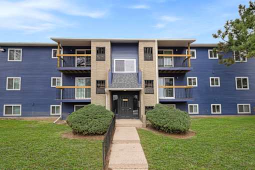 A blue apartment building with a black door and windows.