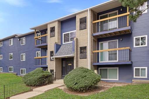A blue apartment building with a black fence in front.