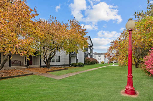 A red street lamp stands on a green lawn.