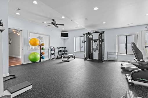 A spacious home gym with a variety of equipment including a treadmill, weights, and a bench press.