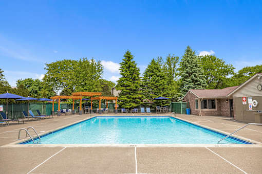 A large swimming pool surrounded by trees and a building with a red roof.