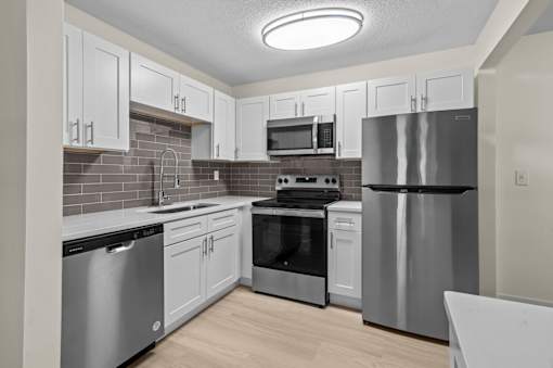 A kitchen with stainless steel appliances and white cabinets.