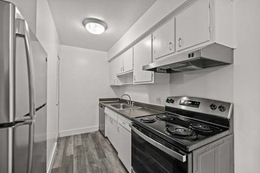 A black and white image of a kitchen with a stove, sink, and refrigerator.