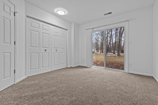 an empty living room with a window and a door to a yard
