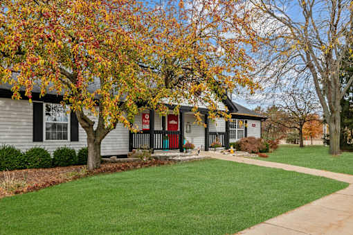 A house with a red door and a tree with orange leaves in front.