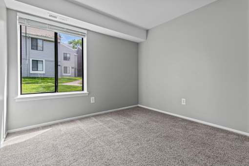 A room with a window showing a house across the street.