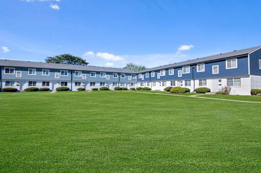 A large grassy area in front of a building with a tree.