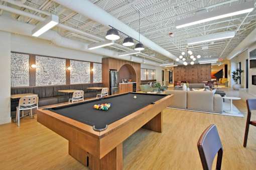 A pool table is in the middle of a room with a couch and chairs.