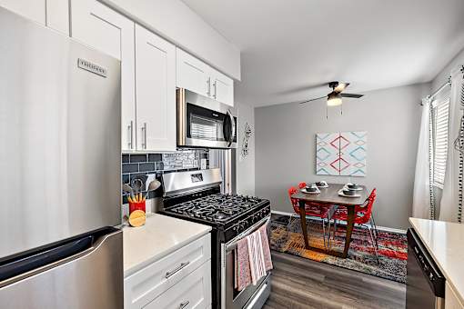 spacious kitchen with stainless steel appliances and white cabinets and a dining room table with chairs