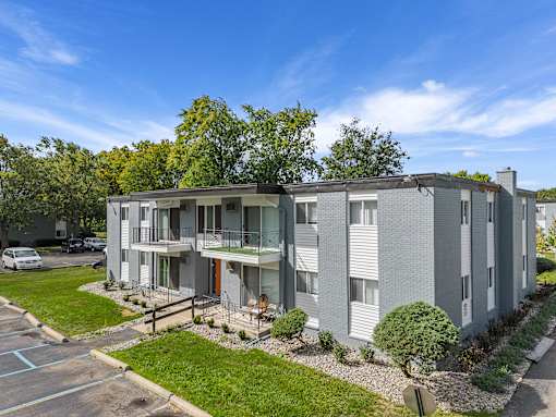 A modern apartment building with a parking lot in front.