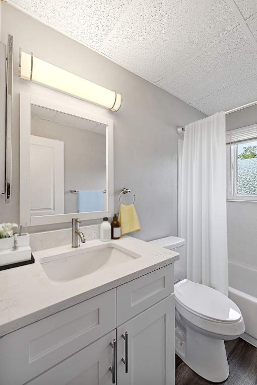 A white bathroom with a sink, toilet, and mirror.
