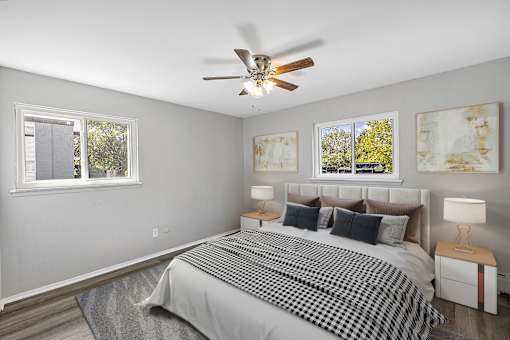 A bedroom with a bed, two lamps, and two paintings on the wall.