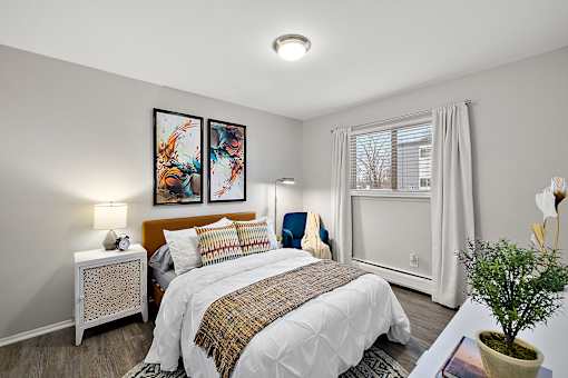 A bedroom with a large bed and two framed pictures on the wall.
