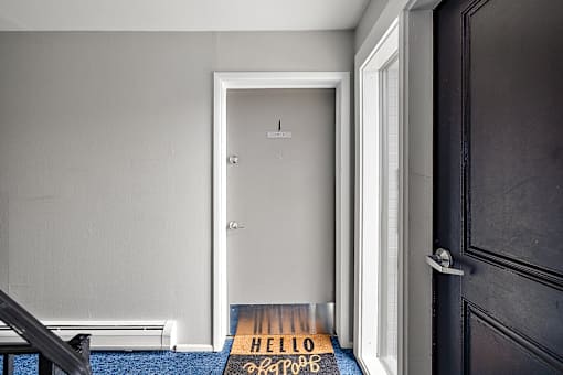 A black door with a mat that says "HELLO" on it.